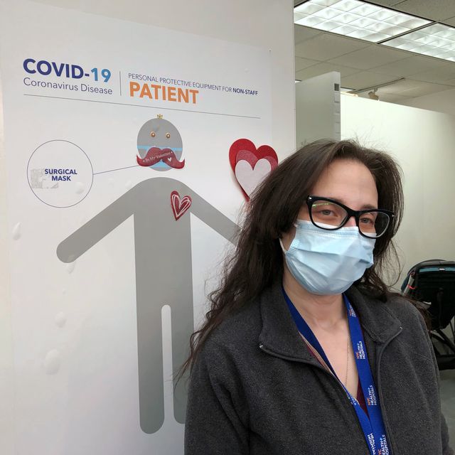 A woman poses in front of a COVID poster